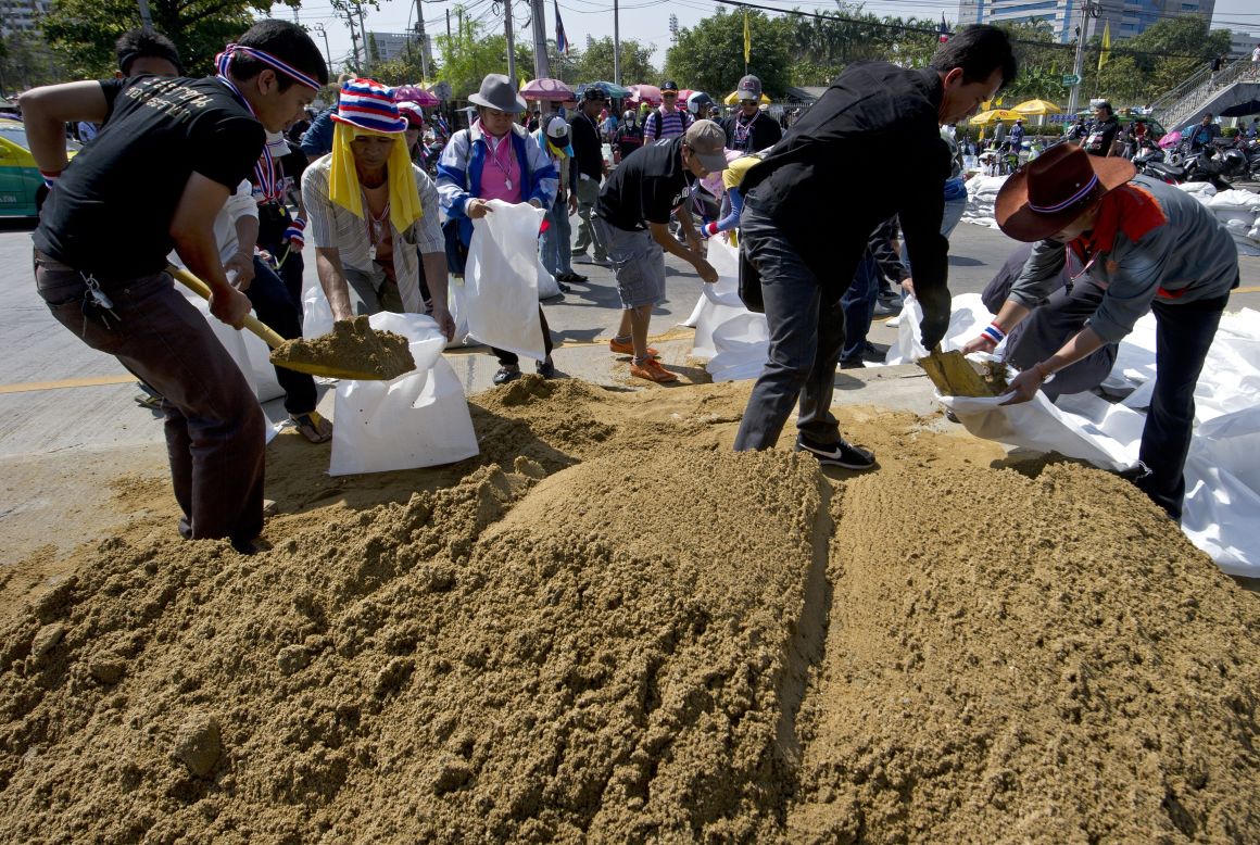 Anti-government protesters fill sandbags as they make barricades during a Bangkok rally on January 13, 2014. 
