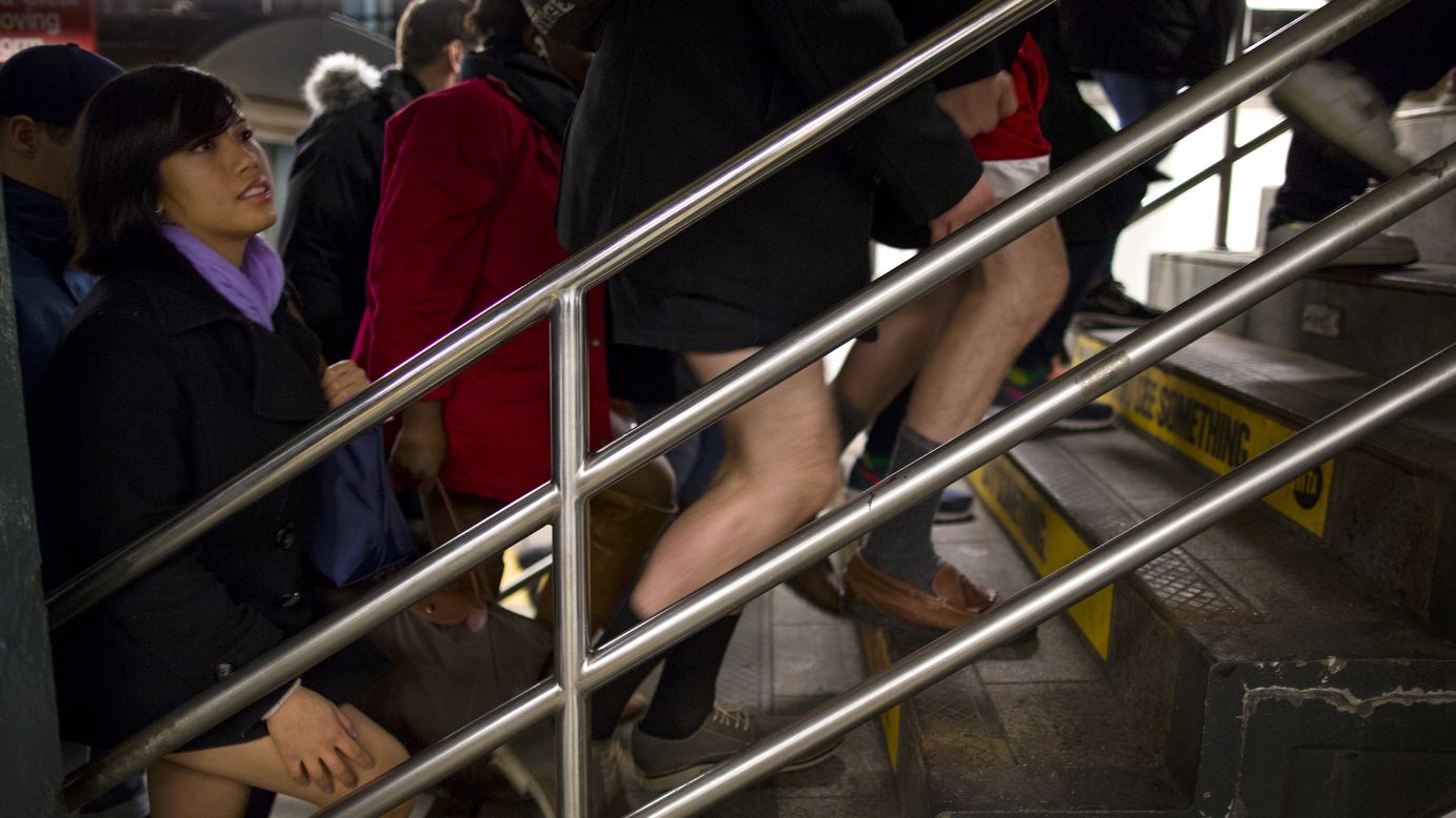 People with and without pants walk up a staircase at a subway station in New York.
