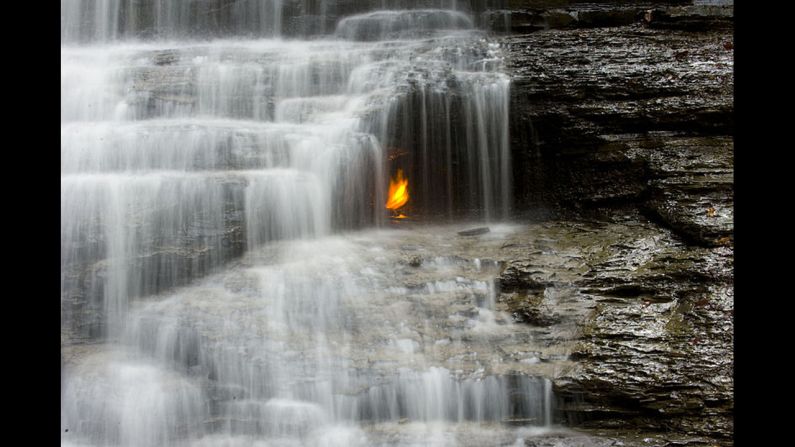A golden flame flickers behind a small waterfall in the Shale Creek Preserve section of Chestnut Ridge Park. A geological fault allows methane gas to escape to the surface, where at some point a visitor set it alight. 