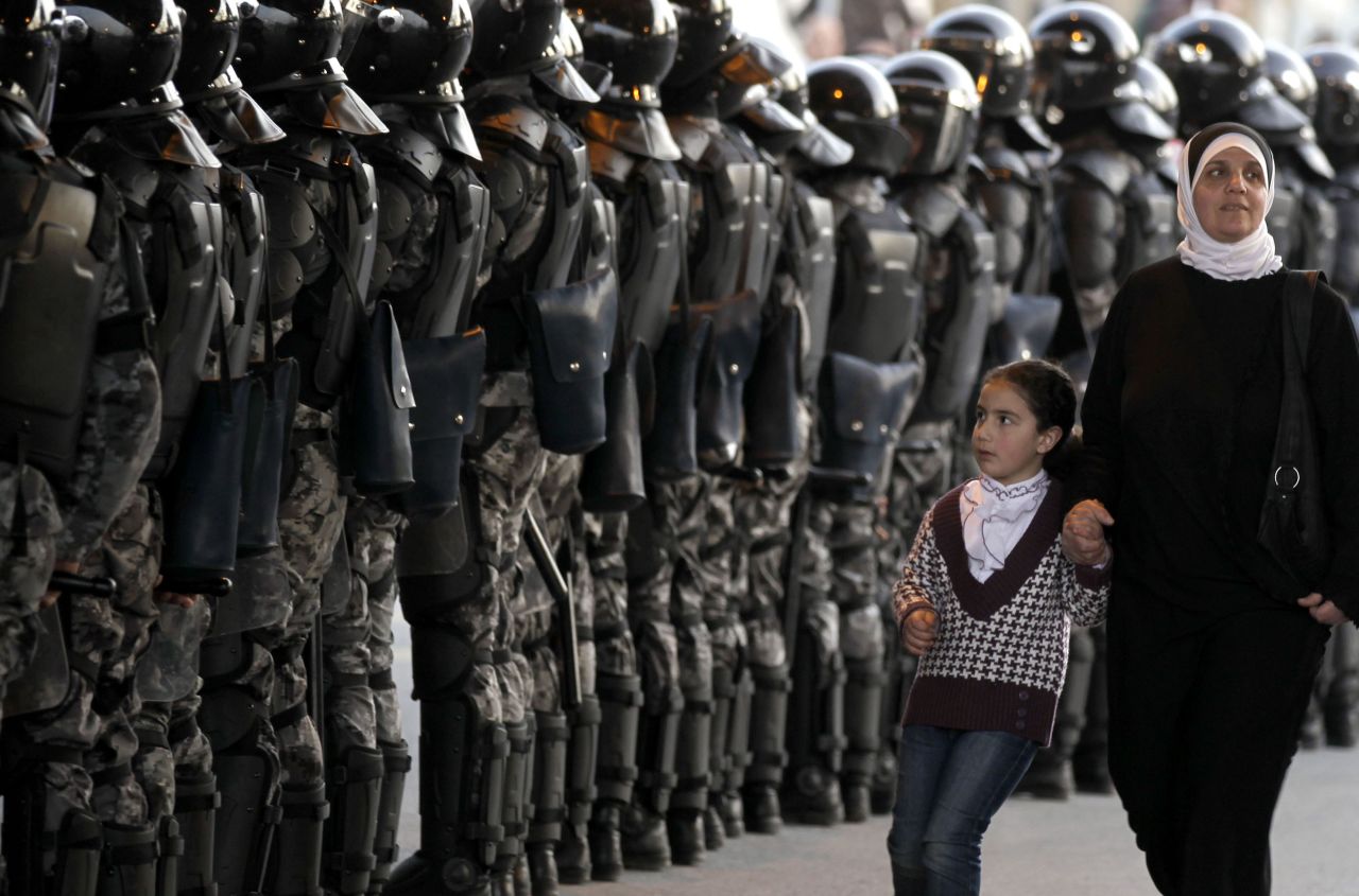 A woman and her daughter walk past Jordanian riot police standing guard at Jamal Abdual Nasser sqaure, in Amman, during demonstrations calling for political reforms in March 2012.