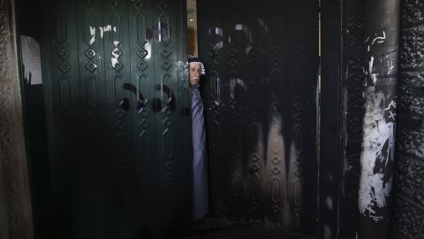 A Palestinian man stands on the doorway of a damaged mosque in the West Bank village of Deir Istiya on January 15, 2014. 
