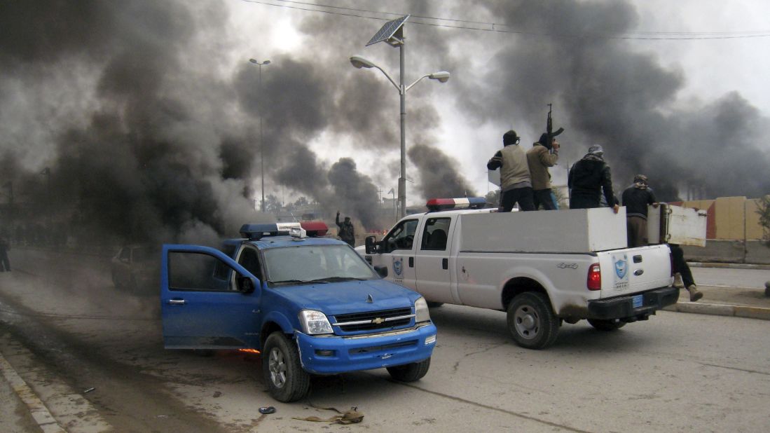 Al Qaeda fighters patrol a street in a commandeered police truck as another police vehicle burns in front of the main provincial government building in Falluja on Wednesday, January 1.