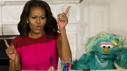 First Lady Michelle Obama dances alongside Sesame Street character Rosita during an event announcing free licensing of Sesame Street characters to promote and market fresh fruit and vegetables by Produce Marketing Association growers, suppliers and retailers, as part of the Let's Move initiative, in the State Dining Room of the White House in Washington, DC, October 30, 2013. 