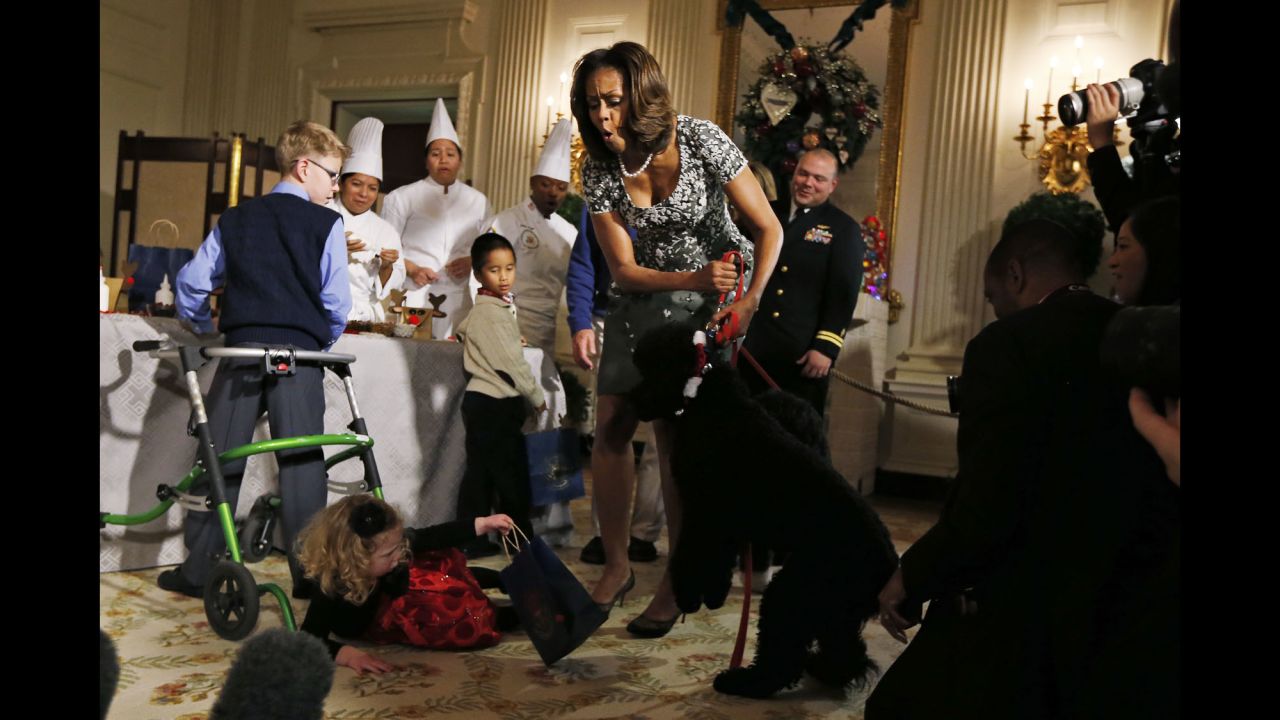 Obama reacts as Ashtyn Gardner, a 2-year-old from Mobile, Alabama, loses her balance while greeting Sunny, one of the Obamas' dogs, at a White House event in December 2014.