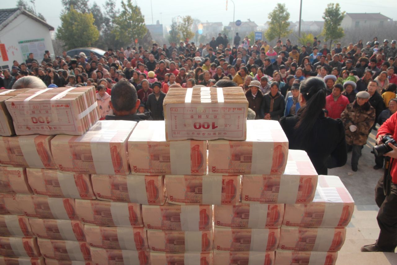 Villagers stand in front of a "money wall" in Sichuan, China waiting to collect their year-end bonus from their investments in January 2014.