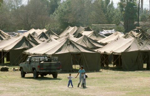 A homeless mother and her children walk near a tent city at Winnetka Recreation Center in Winnetka, California. The National Guard set up shelters for the thousands of victims who lost their homes.