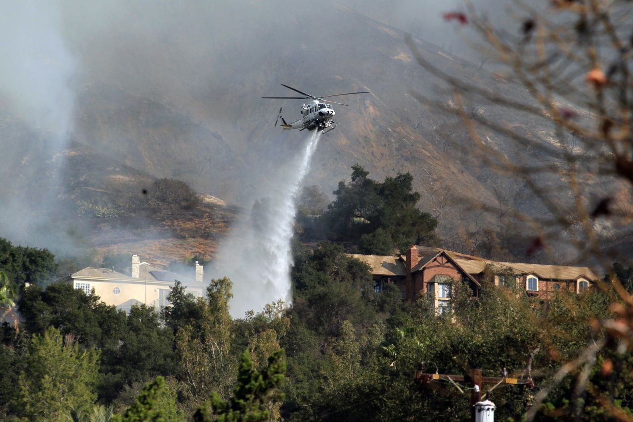 A helicopter drops water over homes in Glendora on January 16.