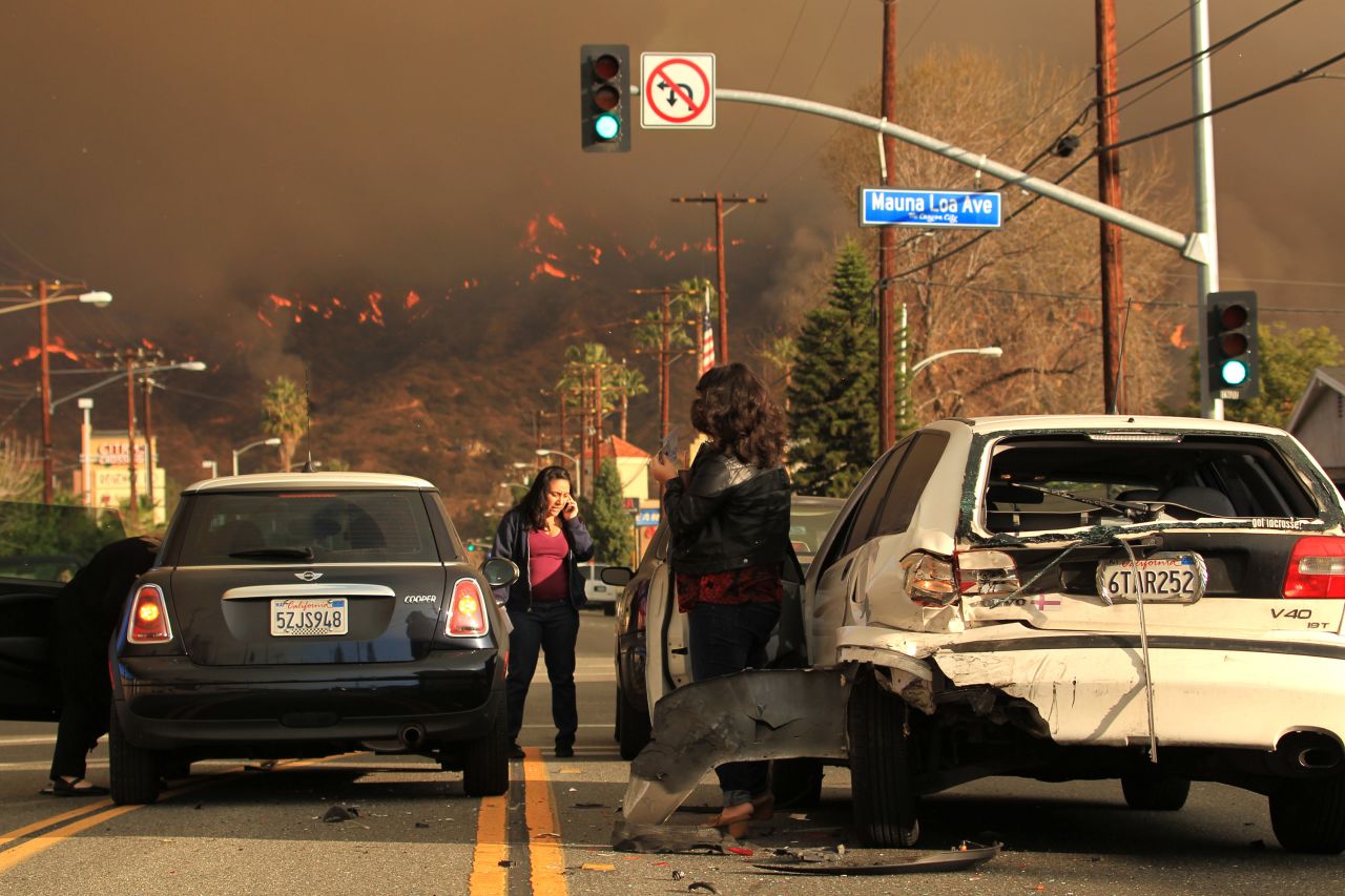 Motorists exchange information after a car accident while the wildfire burns in the Glendora hills on January 16.