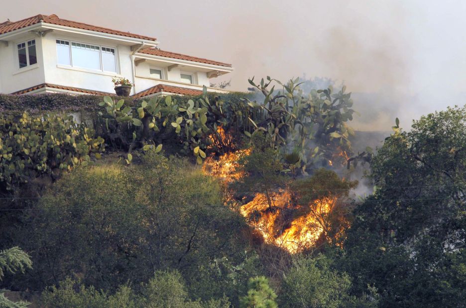 The fire makes it way up a hill toward a house in Glendora on January 16.