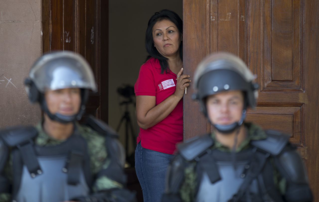 A city employee watches from a doorway as Mexican soldiers guard Apatzingan City Hall on January. 14. Mexican soldiers and federal police have faced tense standoffs with vigilantes after the government campaign to stop violence turned deadly. 