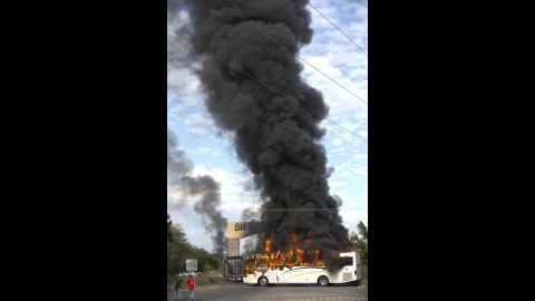 A bus burns at the entrance of Paracuaro on January 10. Some residents have responded to the vigilante groups' arrival by destroying property and setting vehicles ablaze to create road blocks to stop them.