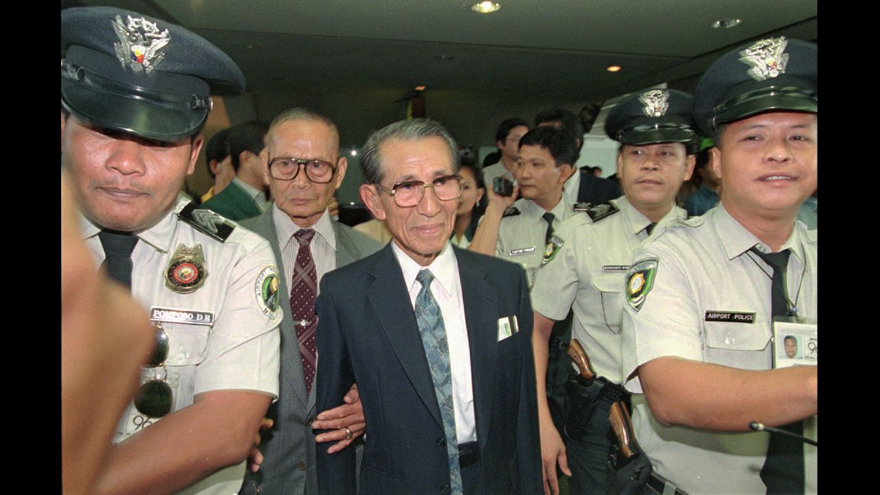 Police escort Onoda shortly upon his arrival in Manila in May 1996. He was a controversial figure in the Philippines, where anger remained over the Japanese occupation. The Philippine government pardoned him, but relatives of people he was accused of killing gathered to demand compensation when he returned to Lubang.
