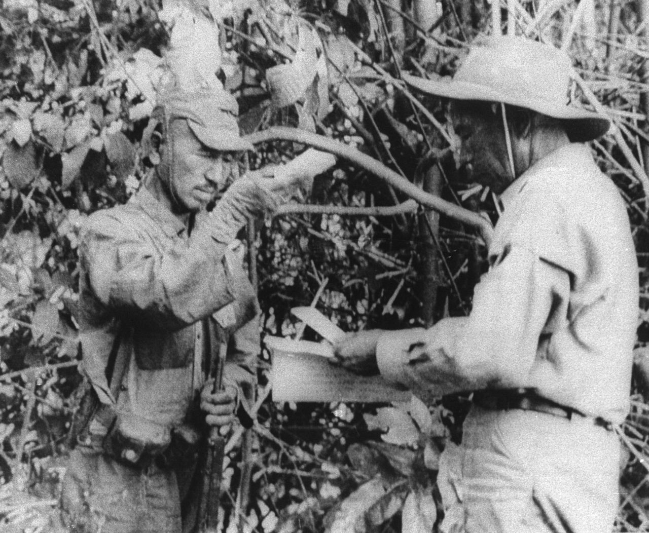 Onoda, left, accepts a pack of cigarettes from a member of a Japanese team sent in 1974 to persuade him the war had ended.
