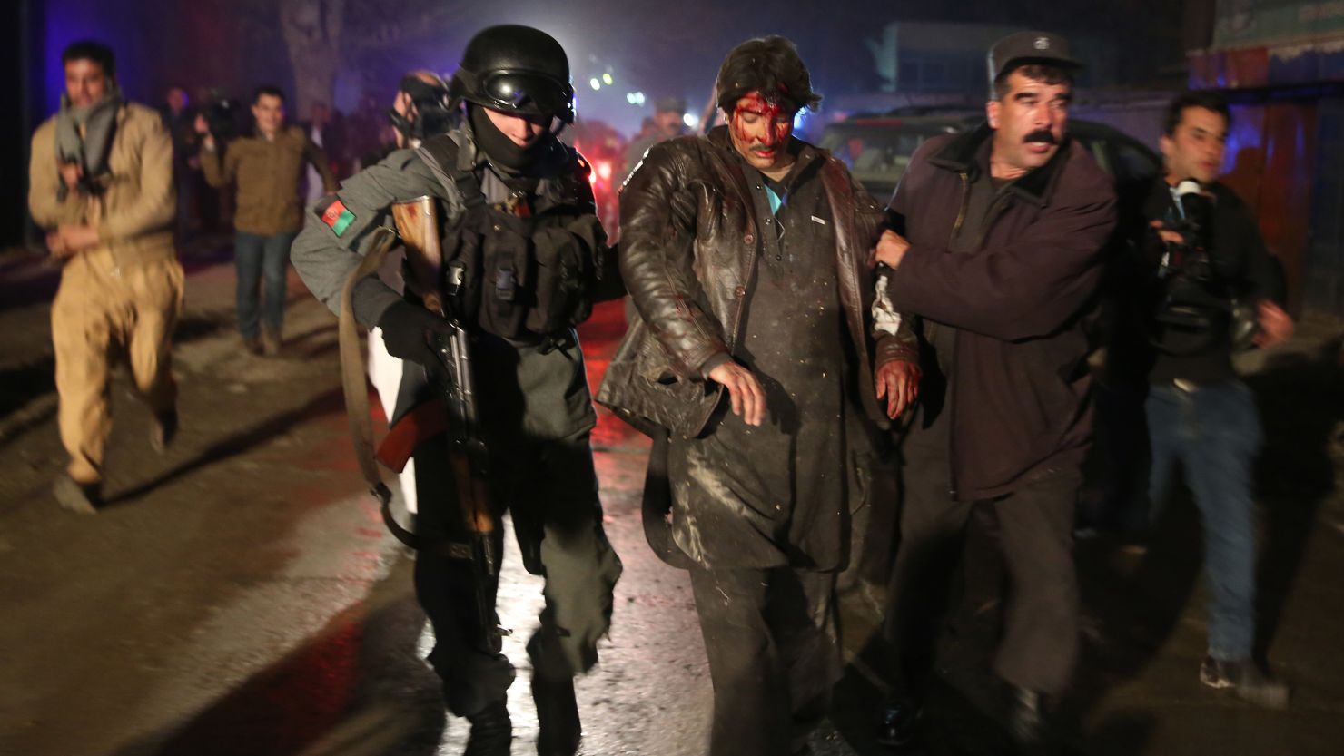 Afghan police forces assist an injured man at the site of an explosion in Kabul, Afghanistan, on Friday, January 17. 