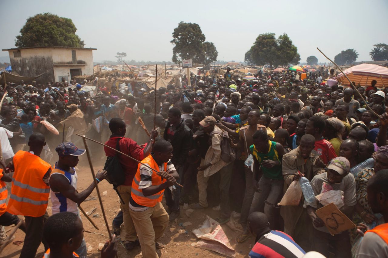 Security volunteers use sticks to fend off people trying to enter a food and supplies distribution point at a makeshift camp at Bangui M'Poko International Airport on Thursday, January 9.