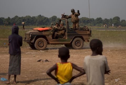 A French soldier waves to children as his jeep patrols the area between an airstrip and a makeshift displacement camp at M'Poko International Airport on January 9.