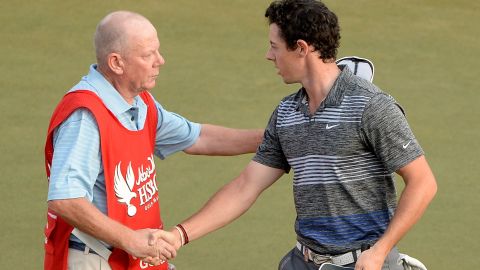 Caddie Dave Renwick (left) is the bearer of bad news for Rory McIlroy on the 18th green in Abu Dhabi