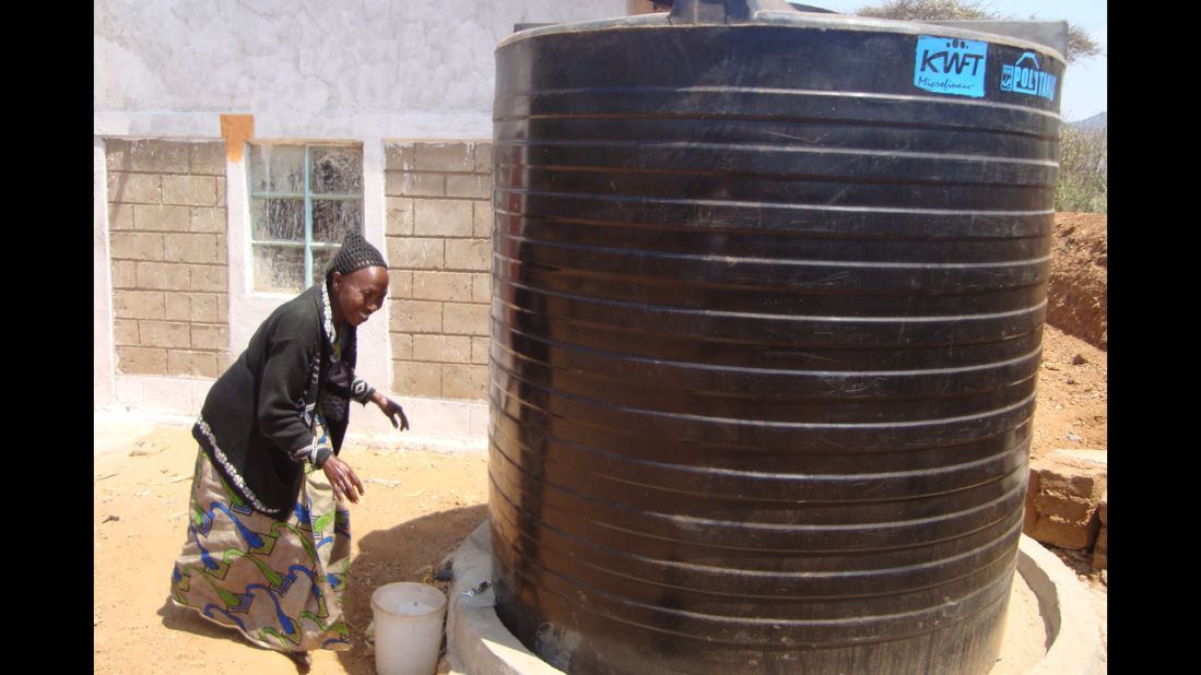 A woman draws water from a collection tank. Borrowers in Kenya are using WaterCredit loans to purchase large water storage tanks. These water tanks provide additional income to families, who sell the water to neighbors or irrigate gardens and fields for better crops.