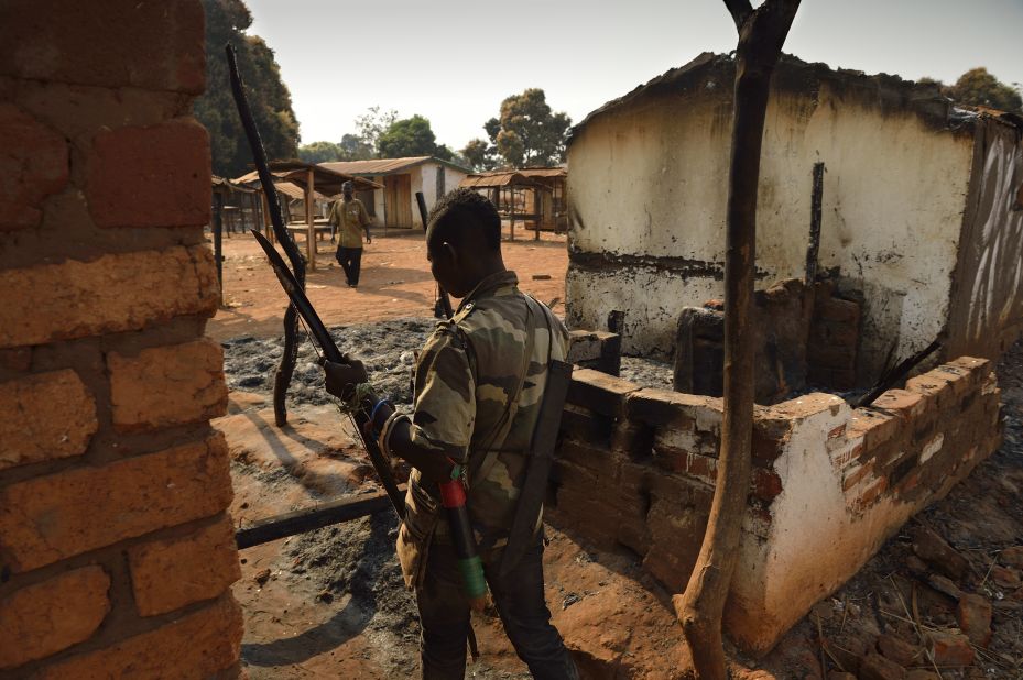 A Christian fighter walks by houses burned by ex-Seleka forces in Bogoura, a small town in the Central African Republic, on Sunday, January 19. The Seleka have been forced out of power since the coup, but Christian militias, known as the anti-balaka, have been allowed to fill the power vacuum, Amnesty International said, with dire consequences for Muslim civilians.