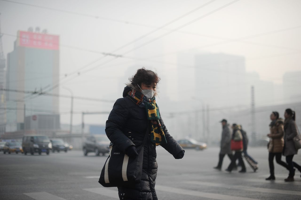A  woman wears a face mask on January 16 as thick smog cuts visibility in the Chinese capital. China has seen a huge increase in coal-burning power plants, and its manufacturing practices aren't nearly as efficient as in the West.