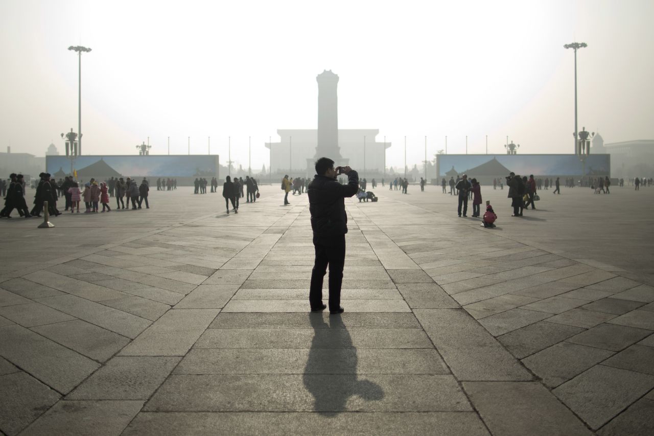 A tourist takes photos during a heavily polluted day in the capital's Tiananmen Square on January 16.