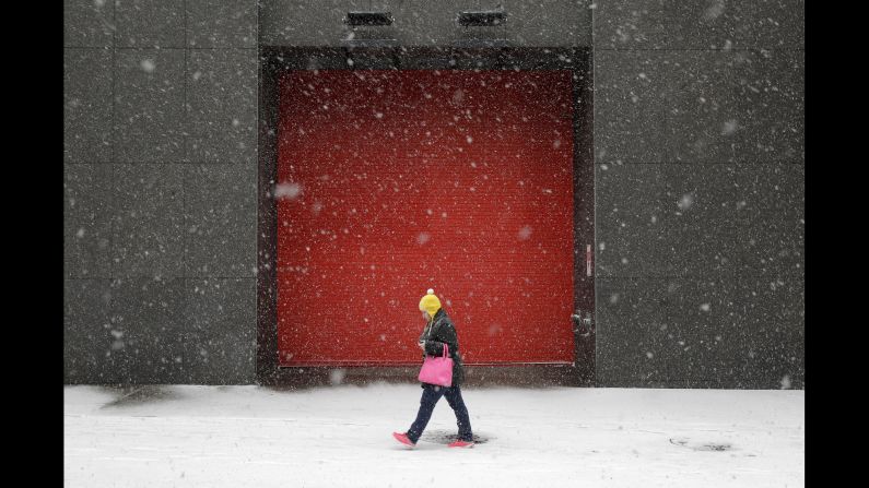 A woman walks in Baltimore as snow falls Tuesday, January 21.