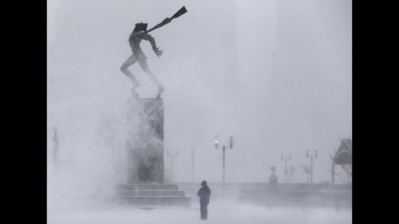 Wind kicks up snow January 21 in front of a statue in Jersey City, New Jersey.