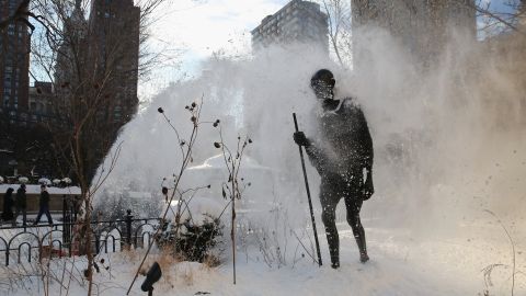 A snow blower clears a sidewalk next to a statue of Mahatma Gandhi at Union Square Park in New York City on January 22.