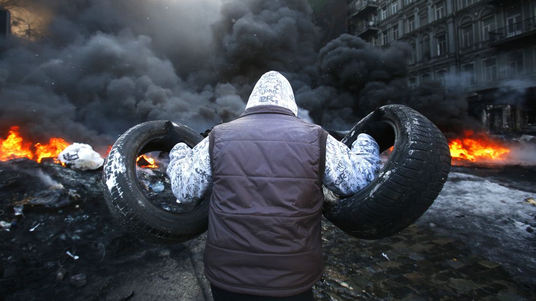 A protester carries tires toward a fire on January 23.