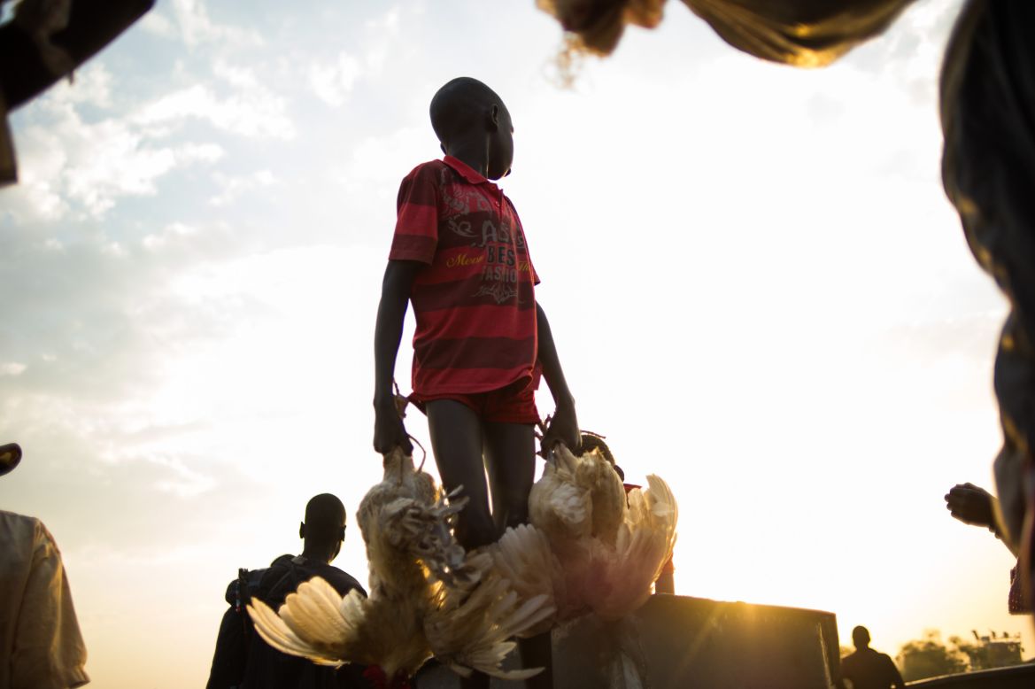 A boy carries chickens off a boat arriving in the village of Minkammen in Awerial county, South Sudan, on Saturday, January 11.