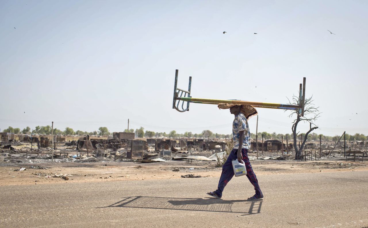 A young man balances a bed on his head as he walks through empty streets and destroyed buildings after government forces retook from rebel forces the provincial capital of Bentiu, in Unity State, South Sudan, on Sunday, January 12.