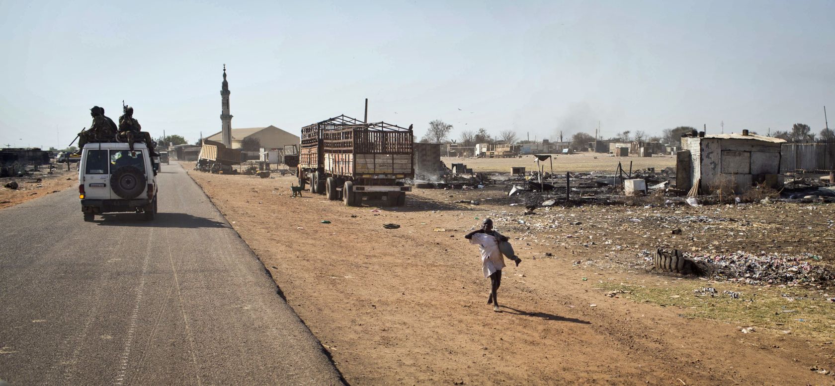 South Sudanese government forces riding on a vehicle through a still-smoldering town pass a boy after government forces retook the provincial capital of Bentiu on January 12.