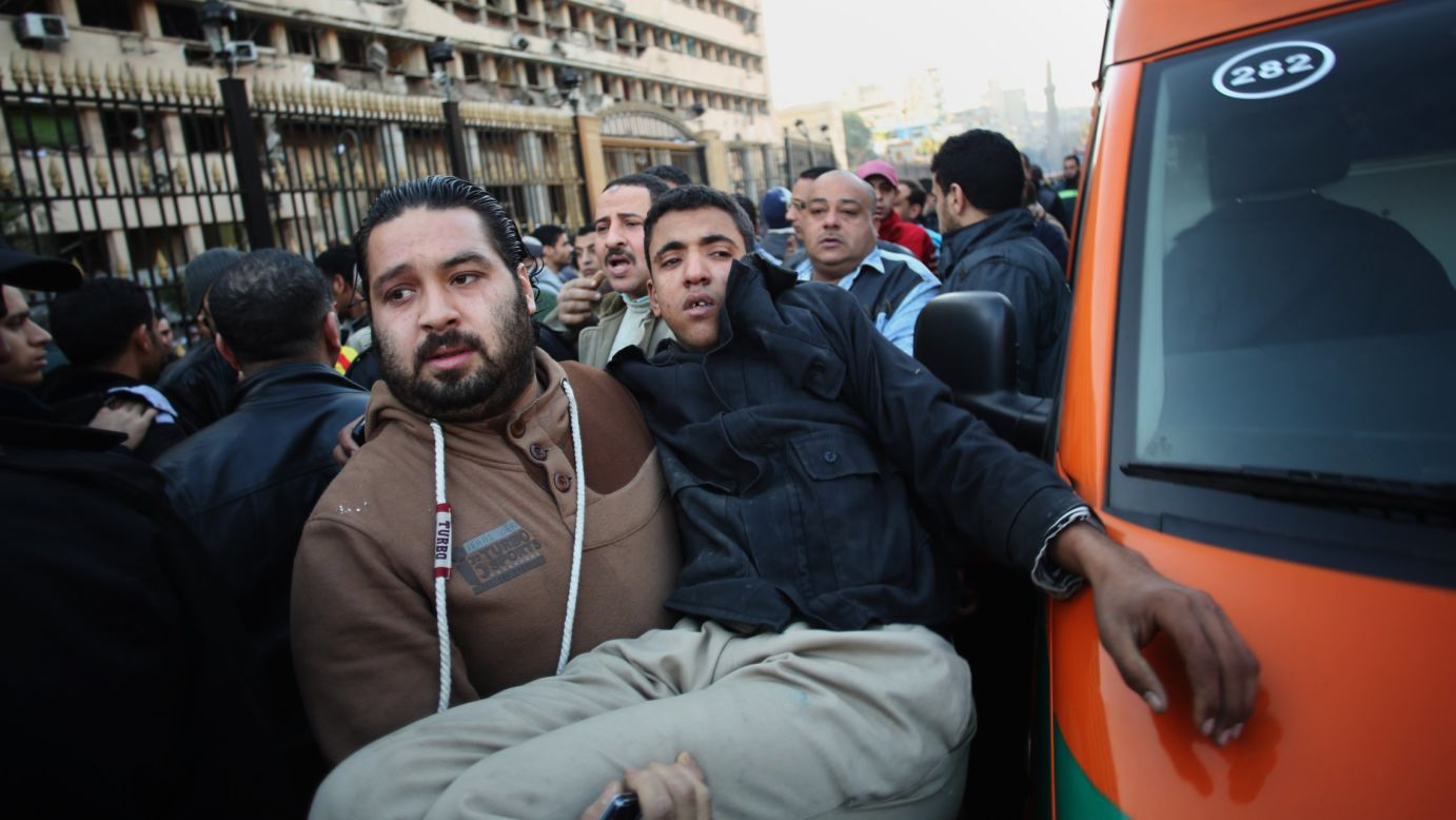 A man carries an Egyptian police officer to an ambulance after a car bomb explosion at the police headquarters in downtown Cairo on Friday, January 24.