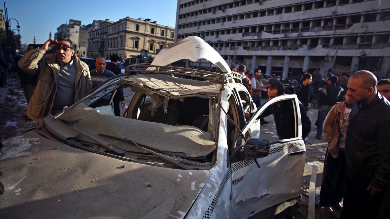 People inspect a destroyed taxi at the site of the explosion.