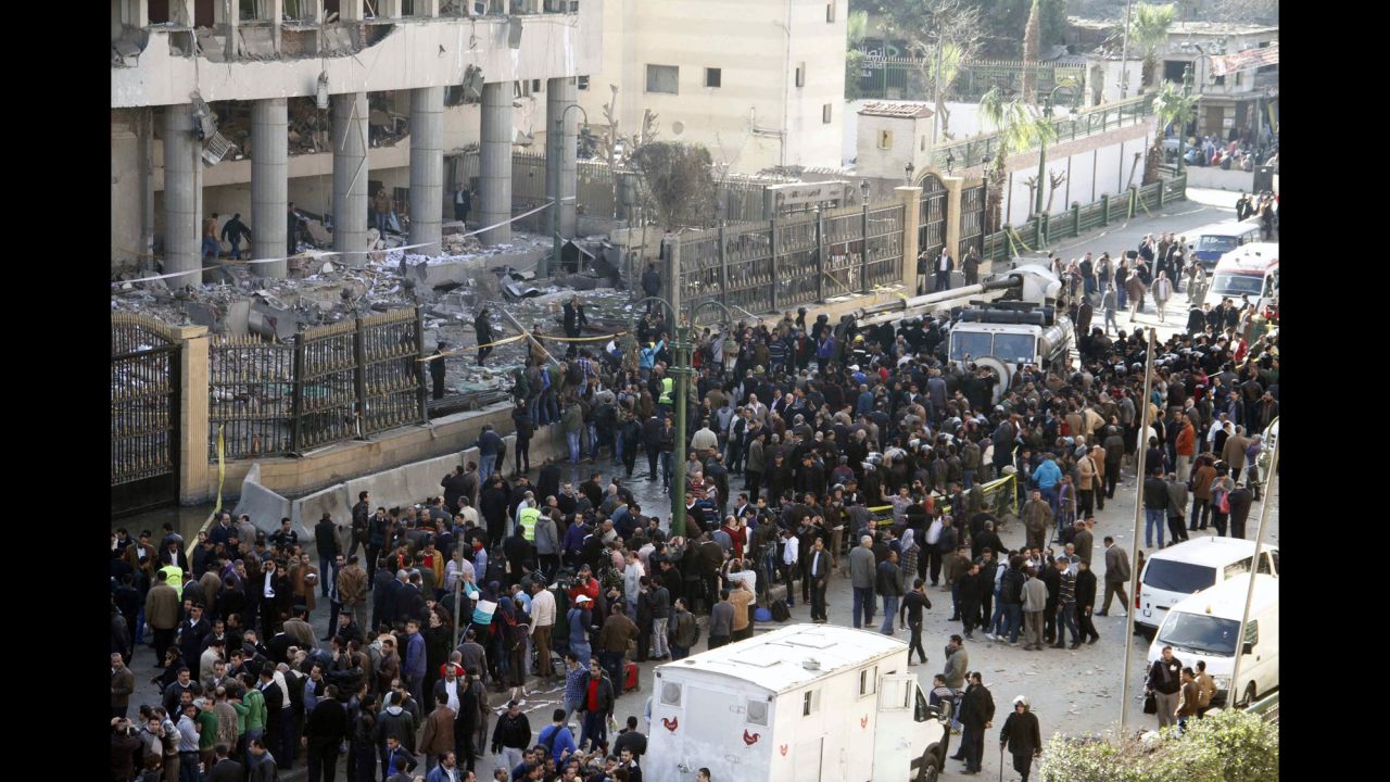 Emergency personnel and bystanders gather outside the police headquarters.