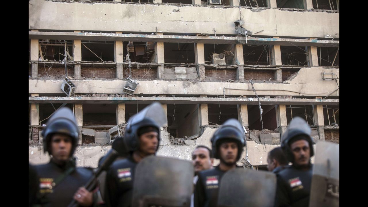 Police stand in front of the damaged facade of the Cairo police headquarters.