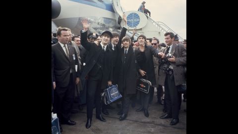 The band waves to cameras at John F. Kennedy International Airport.