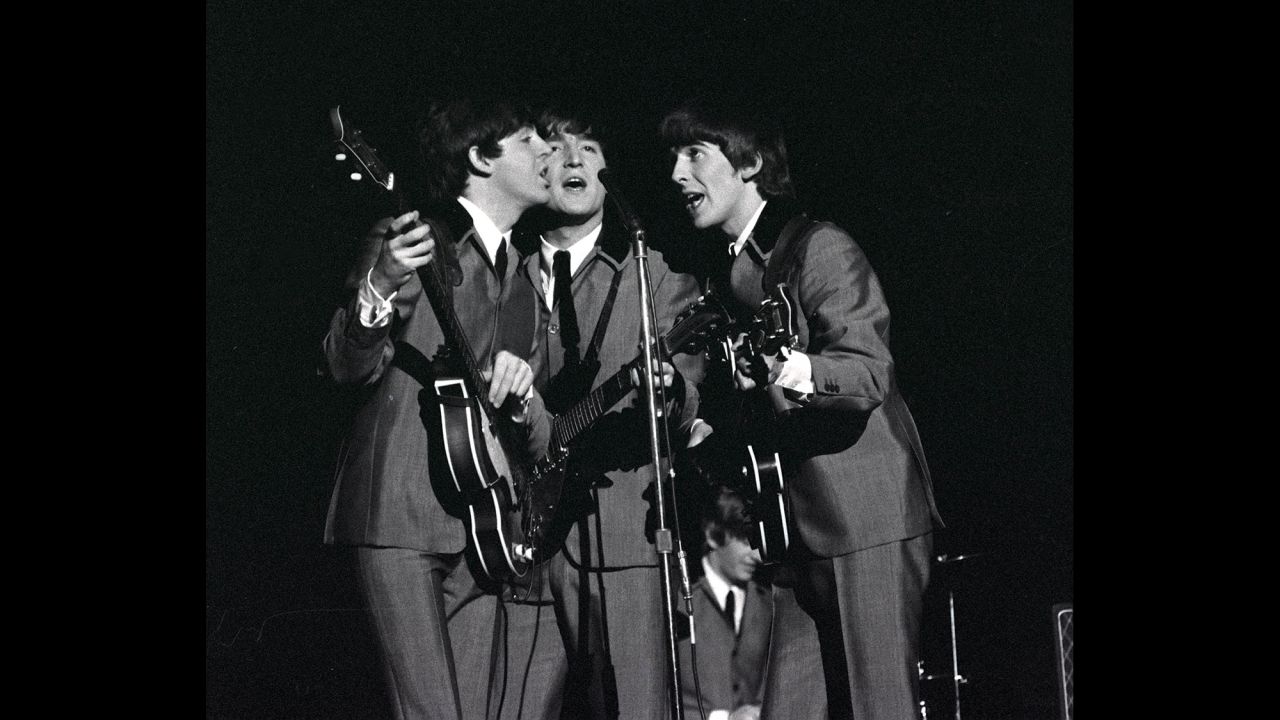 From left, McCartney, Lennon and Harrison share a microphone as they sing a song at Carnegie Hall.