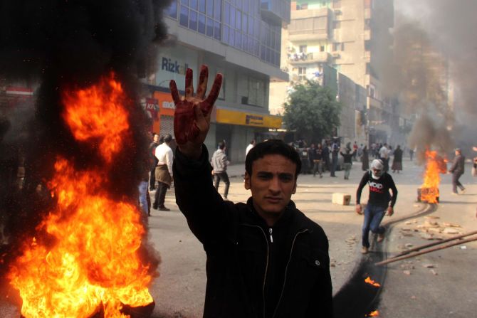 A supporter of the Muslim Brotherhood flashes a four-fingered salute next to burning tires allegedly set ablaze by protesters during clashes with security forces.