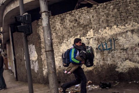 A man carries his son to escape clashes between police and anti-military protesters.