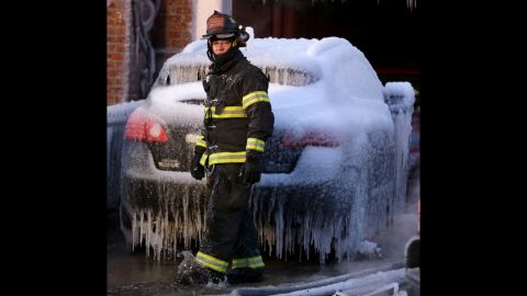 A North Hudson County firefighter walks in front of an ice-covered vehicle near a building where a six-alarm fire was put out January 24 in Union City, New Jersey.