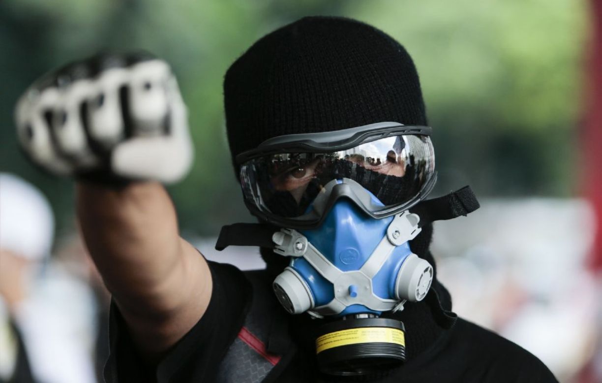 A man wearing a gas mask participates in the protest. 