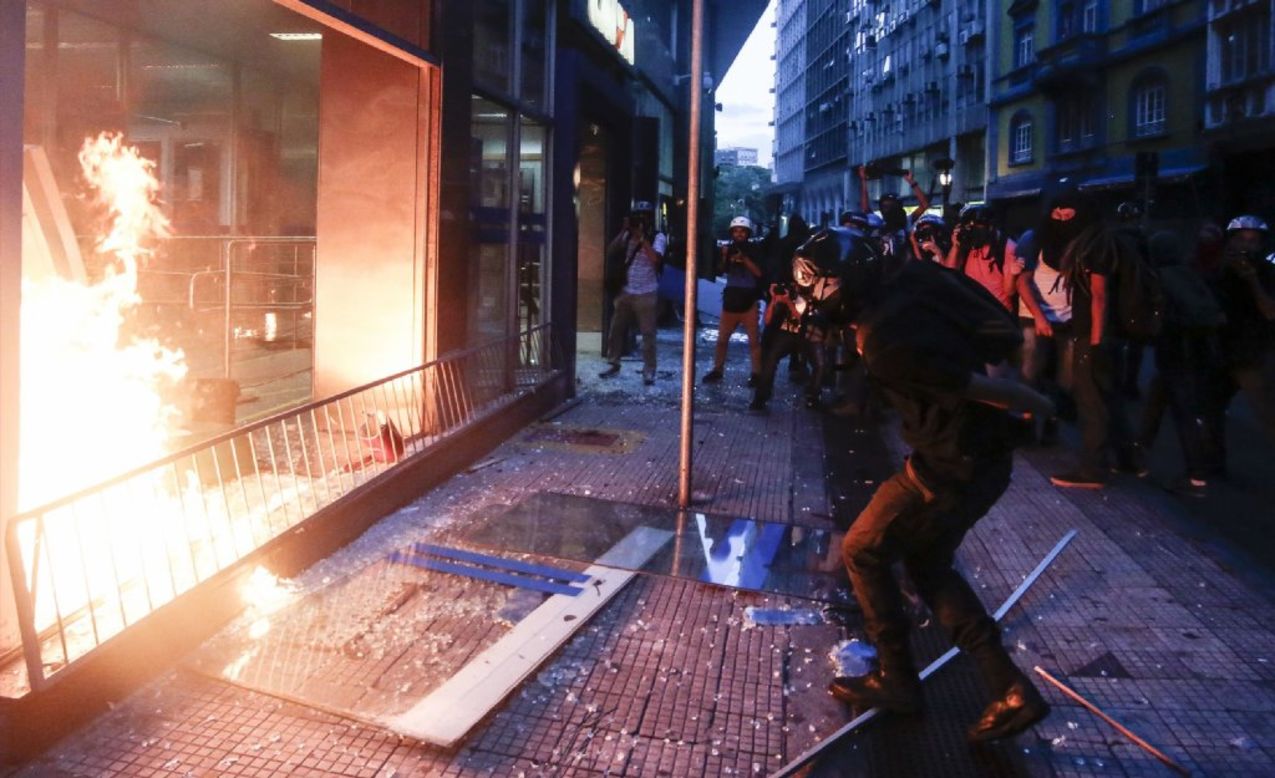 Demonstrators attack and set fire to a bank.