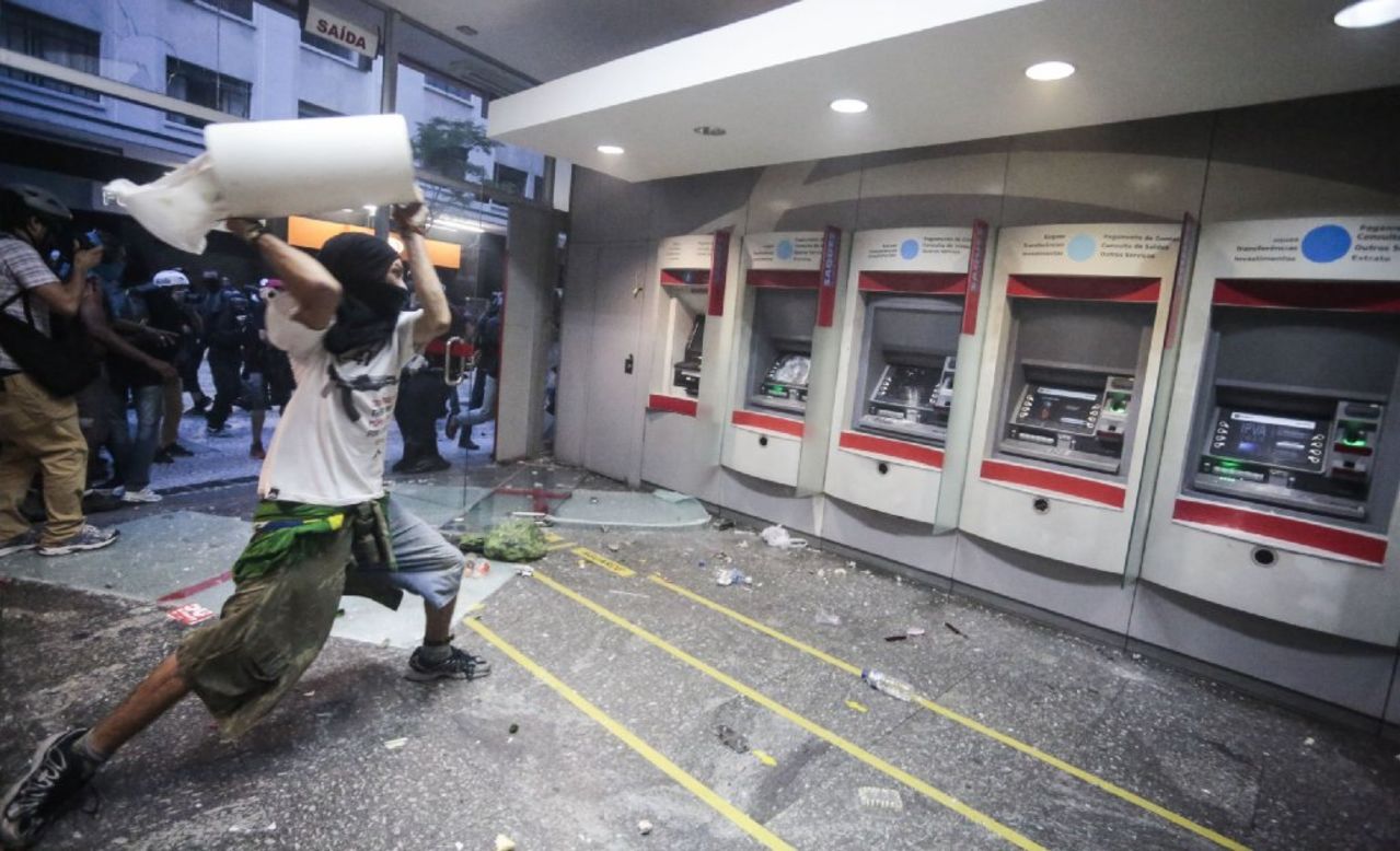 A protester throws debris at a line of ATMs. 