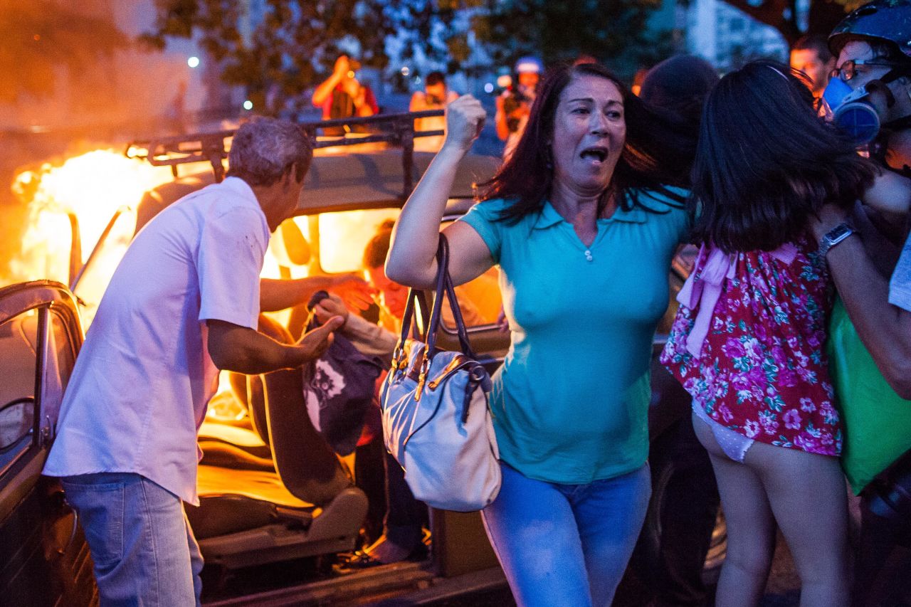 People help a family out of a burning car in Sao Paulo last January after it drove over a barricade of fire started by protesters, during demonstrations against the staging of the World Cup.