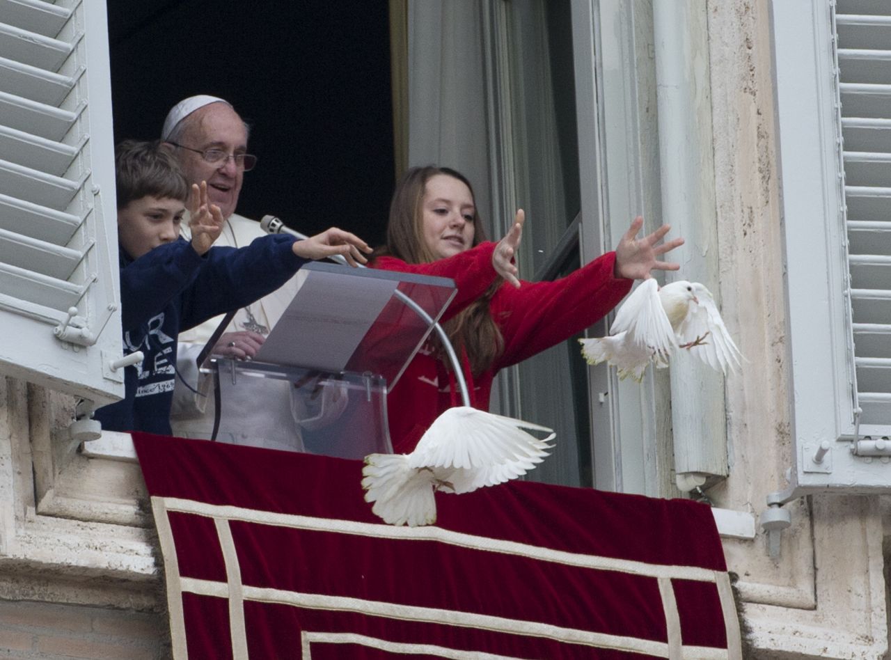 El papa Francisco observa mientras dos niños sueltan palomas desde su ventana hacia la Plaza de San Pedro en el Vaticano el domingo. Las palomas fueron atacadas poco después por un cuervo y una gaviota.