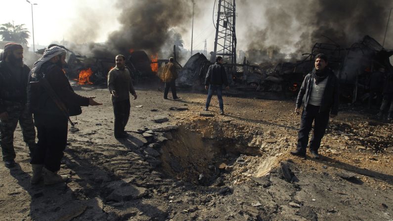 Los rebeldes y los civiles echan un vistazo a un cráter que los activistas dicen que es el resultado de un ataque aéreo del gobierno sirio en una estación de autobuses de Alepo el martes 21 de enero. 