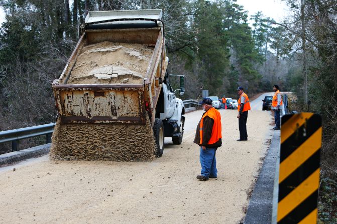 Workers dump sand across a bridge in Covington, Louisiana, on January 27.