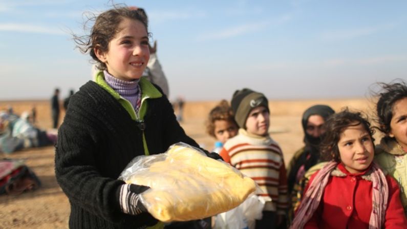 Syrian refugee Hala had been on the road for two days when she arrived in Jordan.  She smiles at Sweaters for Syria volunteers handing out winter clothes.