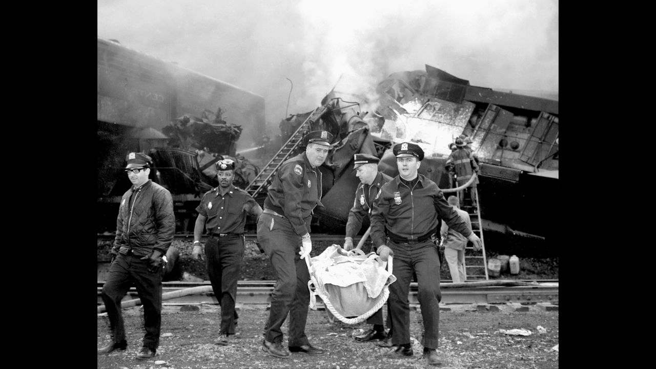 Patrolmen carry one of the dead from the wreckage caused when two trains crashed in a New York freight yard on May 22, 1967. Six crew members died and four more were injured.